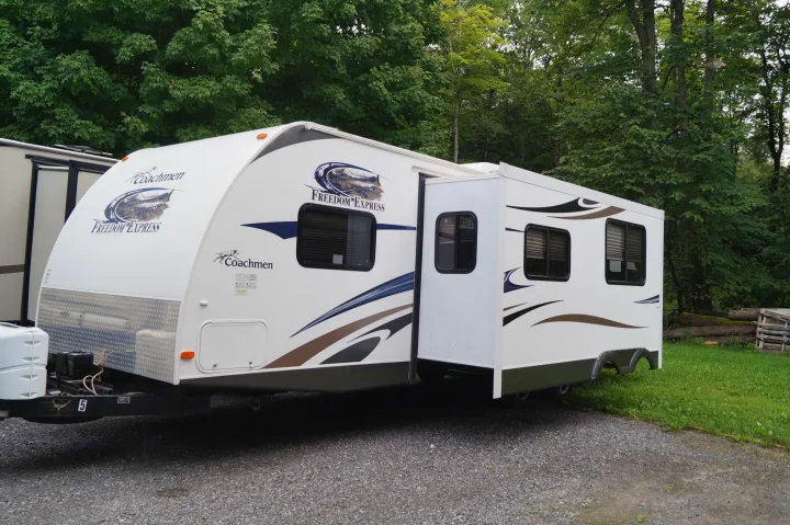 White Coachmen Freedom Express travel trailer with slide-out extended, parked on gravel, great for an RV rental.. Coachmen Freedom Express 2017