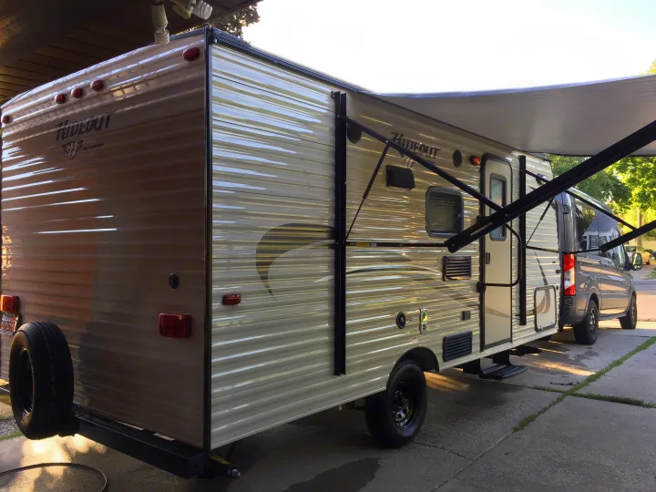 Explore the outdoors! A light-colored Hideout travel trailer, perfect for an RV rental adventure, parked on concrete with awning out.. Keystone Hideout 2016