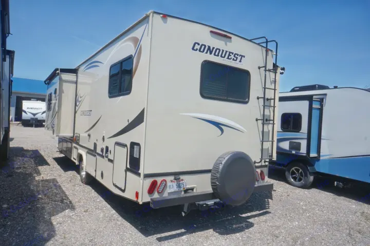 This Conquest Class C RV, ideal for an RV rental, shows its extended side, rear with ladder and spare tire, parked outside.. Gulf Stream conquest 2020