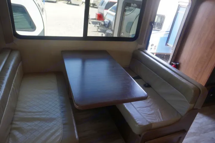Interior view of an RV rental showing the dinette with a wooden table and two comfortable cushioned benches.. Gulf Stream conquest 2020