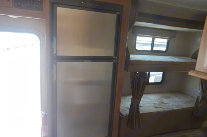 Inside an RV rental, featuring a stainless Dometic refrigerator, bunk beds, and a fire extinguisher near the door.. Gulf Stream conquest 2020