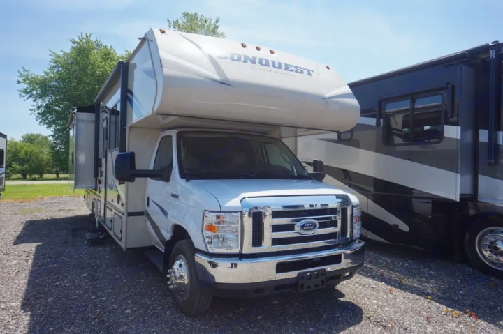 This white Conquest Class C motorhome, an ideal RV rental, is parked on gravel. It features a Ford front, ready for adventures.. Gulf Stream conquest 2020