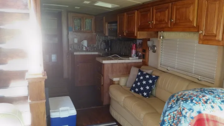 Step into this RV rental's cozy interior, showcasing a comfortable sofa, full kitchen with wood cabinets, and large window.. Airstream Skydeck 2008