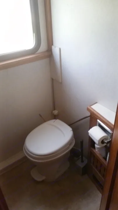 RV rental bathroom showing a compact toilet, window, and toilet paper holder.. Airstream Skydeck 2008