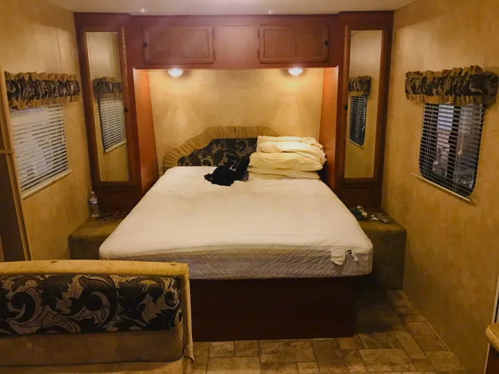 This inviting RV rental bedroom features a cozy bed, ample overhead storage, and mirrored closets for a comfortable stay.. K-Z Manufacturing Sportsmen 2011