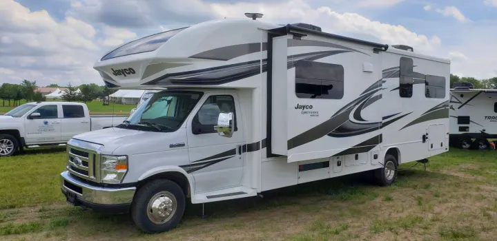 A white Jayco Greyhawk Prestige motorhome, an ideal rv rental, parked on grass under a cloudy sky.. Jayco Greyhawk 2019