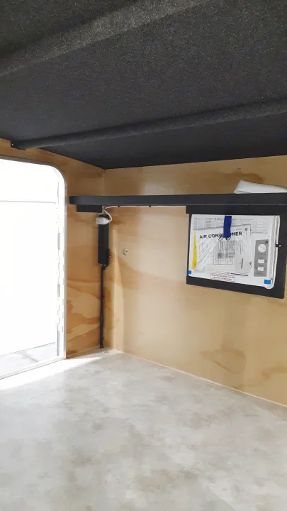 RV rental interior showing wall-mounted air conditioner, dark acoustic lining, and wood paneling with water stains.. Runaway Campers Rangerunner 2019
