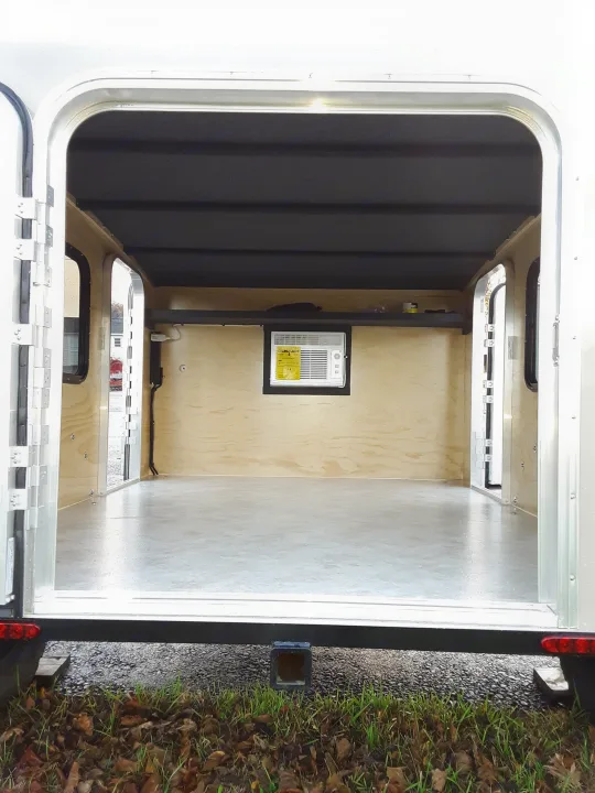 Compact RV rental interior featuring wooden walls, a built-in sleeping area, and a window AC unit. Ideal for travel.. Runaway Campers Rangerunner 2019