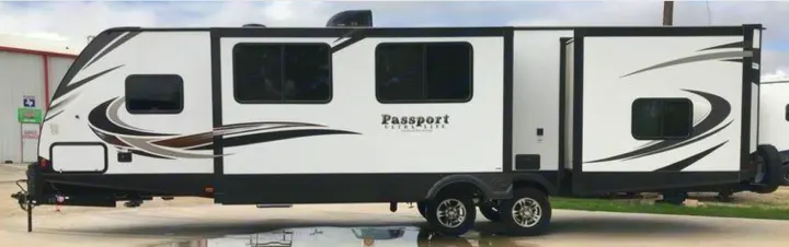Modern white Passport travel trailer with black/grey decals and a slide-out, perfect for your next rv rental adventure.. Keystone Passport 2019