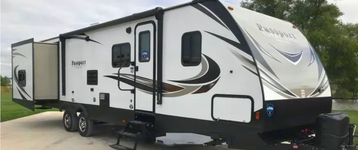 Spacious white Passport travel trailer RV rental, parked with slide-out extended. Ready for your next outdoor adventure.. Keystone Passport 2019