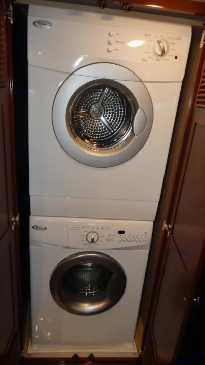 Stacked white compact washer and dryer unit in a cabinet, ideal for an RV rental.. Newmar Essex 2018