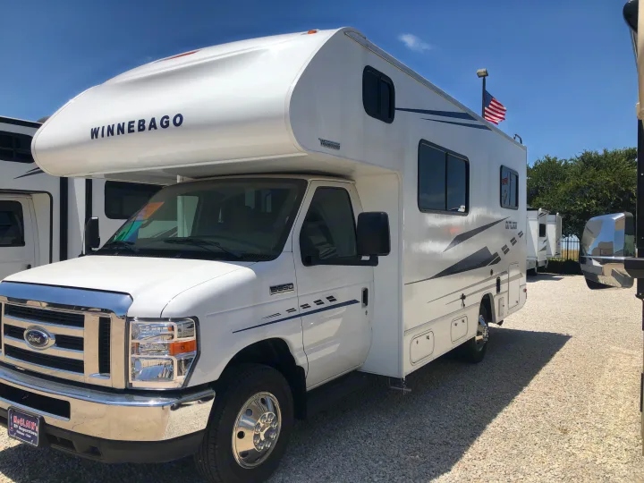 Discover this white Winnebago Class C RV rental, a motorhome parked on a gravel lot, ready for adventure.. Winnebago Outlook 2019