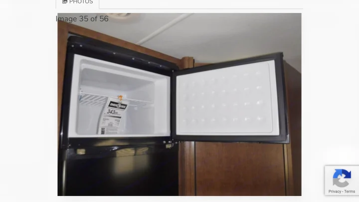 An rv rental's compact mini-fridge/freezer unit is open, revealing the freezer compartment with an energy sticker.. Winnebago Outlook 2019
