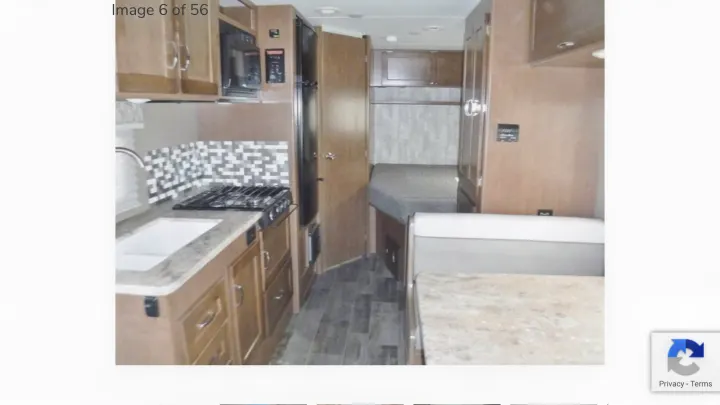 This RV rental interior shows a compact kitchen with stove, sink, and microwave, plus a dining area and sleeping space.. Winnebago Outlook 2019