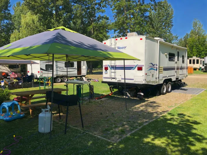 Enjoy your RV rental experience! A spacious campsite with a travel trailer, shade canopy, picnic table, and grill ready for use.. Terry 285j 1999