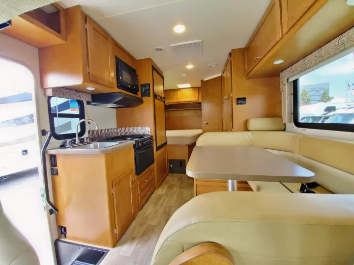 Bright RV rental interior showing kitchen, dining booth, and sleeping area.. Winnebago Minnie Winnie 2018