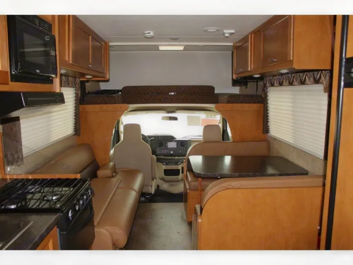 An RV rental interior with a kitchen, dining booth, and an overhead sleeping area, offering a complete mobile living space.. Winnebago Minnie Winnie 2018