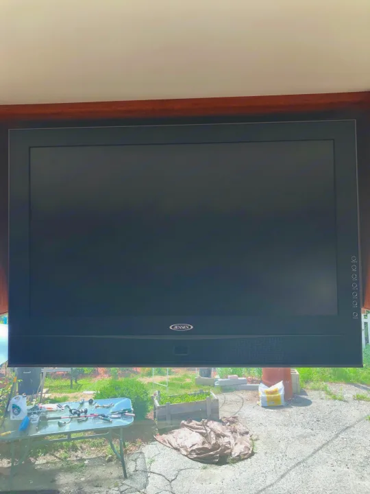 A Jensen TV mounted indoors, reflecting an outdoor view of a yard with fishing gear. Perfect for an RV rental stay.. Ford Coachman 2009