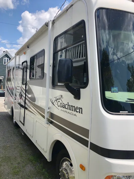 Explore in style with this white Coachmen Mirada RV rental, featuring sleek side stripes and an awning for your adventure.. Ford Coachman 2009