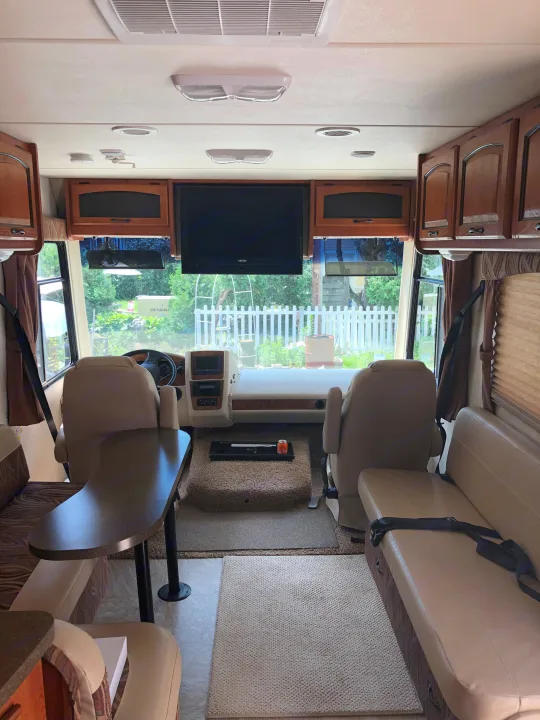 Inside this comfy RV rental: front cockpit area, dining booth, and sofa. A perfect motorhome for road trips!. Ford Coachman 2009