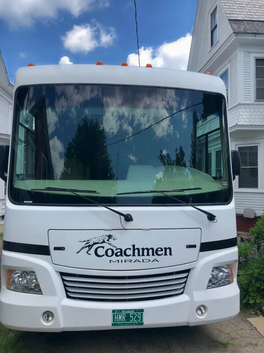 This white Coachmen Mirada RV rental is parked, showcasing its front and distinctive logo.. Ford Coachman 2009