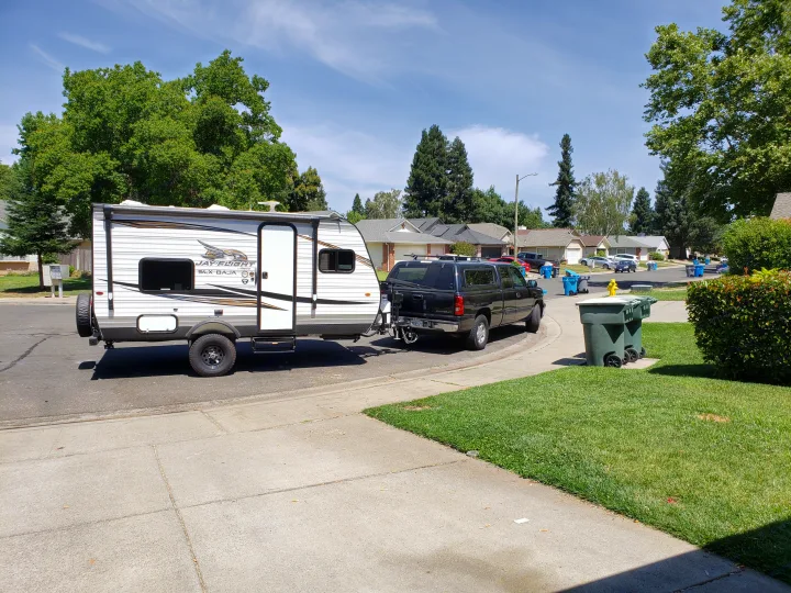 Jayco travel trailer hooked to SUV, ready for an RV rental adventure on a sunny suburban street.. Jayco Jay Flight 2019