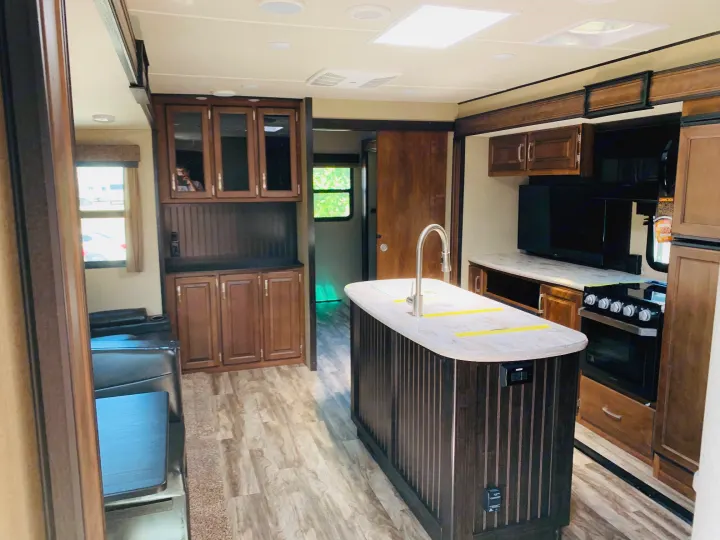 Spacious RV rental interior featuring a modern kitchen island, stove, and comfortable living area for travel.. Grand Design Reflection 2019