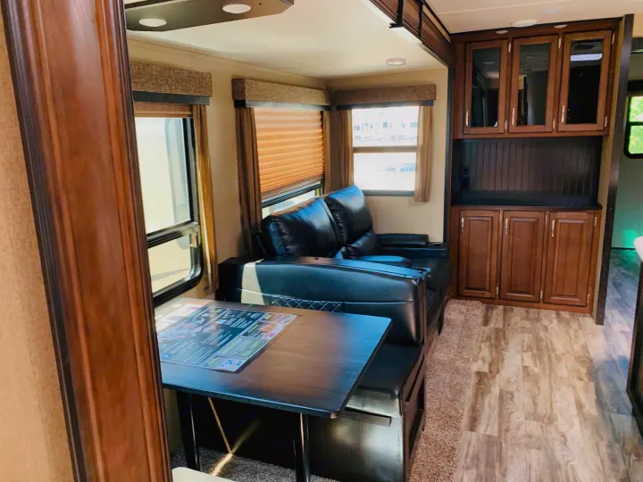 Spacious RV rental living area with dining, reclining sofa, and wood storage cabinets.. Grand Design Reflection 2019