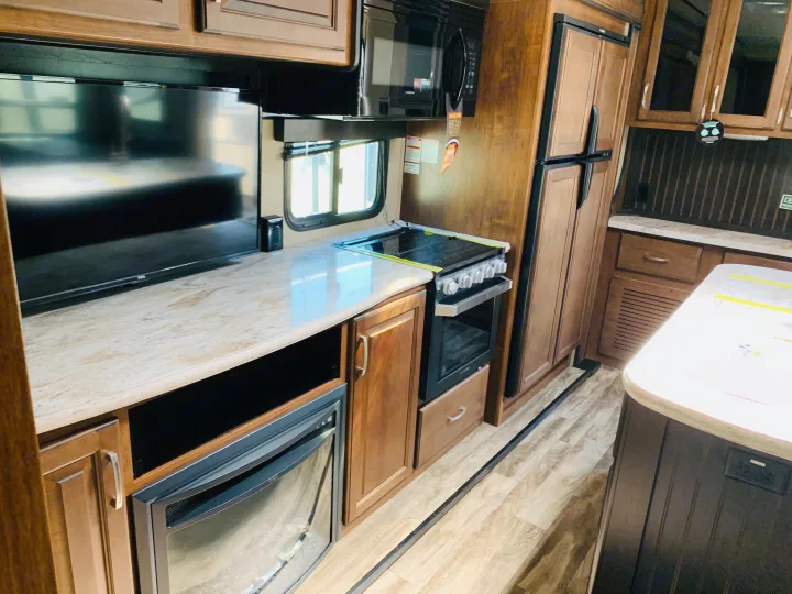 Explore this well-appointed RV rental interior, featuring a full kitchen with stove, microwave, fridge, TV, and fireplace.. Grand Design Reflection 2019