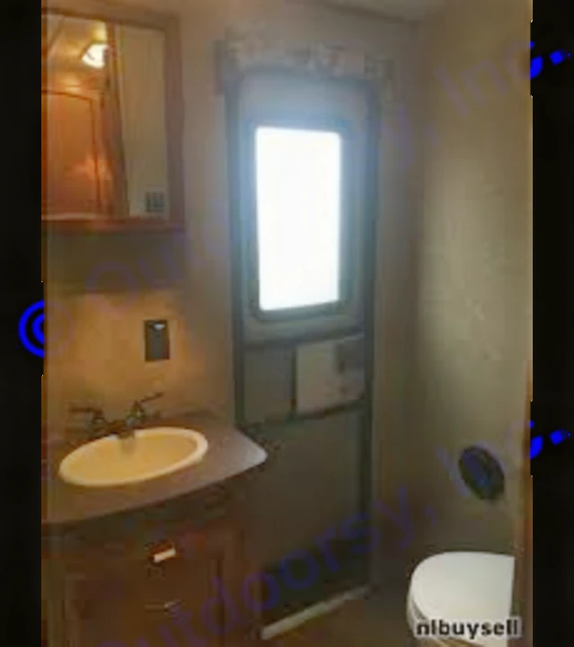 Compact RV rental bathroom featuring a sink, mirror, toilet, and a bright exterior door.. Crossroads Sunset Trail Reserve 2014