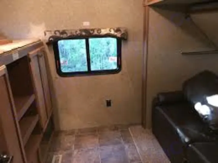 RV rental interior with compact living. Features a window, wood cabinetry, and a black couch for comfortable travel.. Crossroads Sunset Trail Reserve 2014
