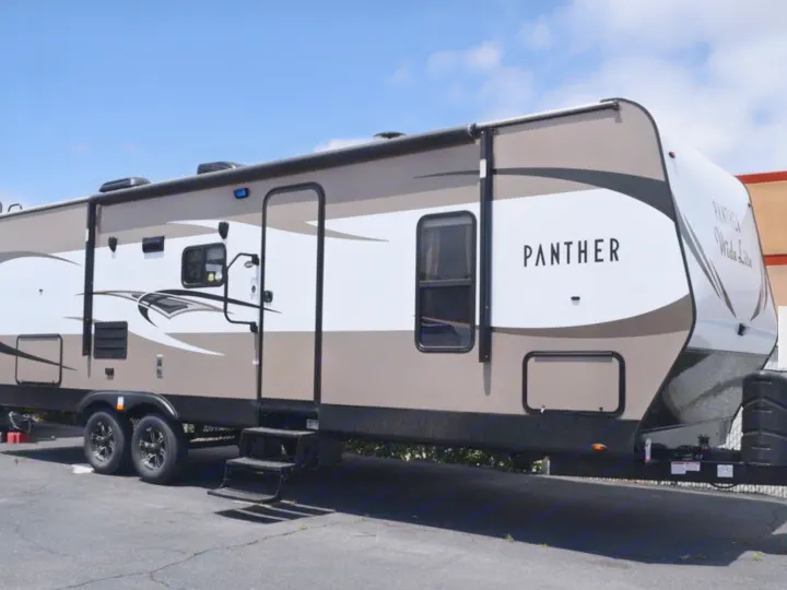 This spacious Panther travel trailer, with its modern tan and white design, is ideal for an RV rental adventure.. Pacific Coachworks Panther BHSS 2019