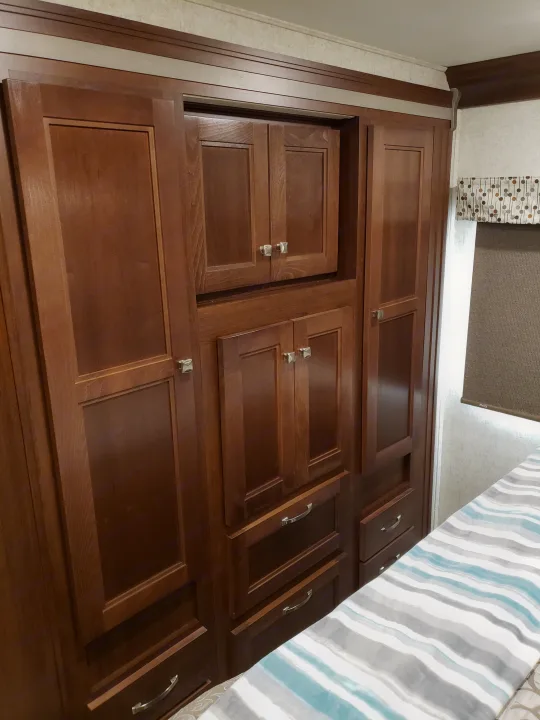 RV rental storage: detailed view of integrated wooden wardrobe, cabinets, and drawers inside the bedroom.. Other Other 2019