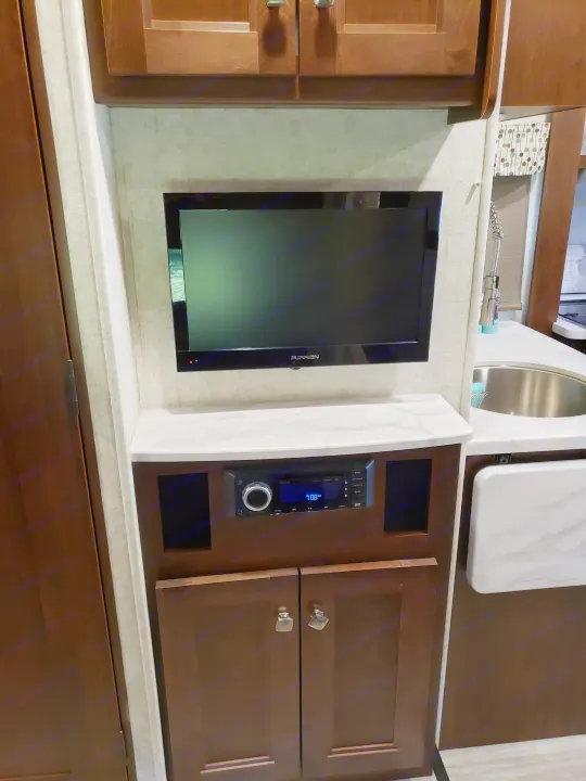 RV rental interior: TV, stereo unit (7:08 AM display), and storage cabinets. A small counter with a sink is to the right.. Other Other 2019