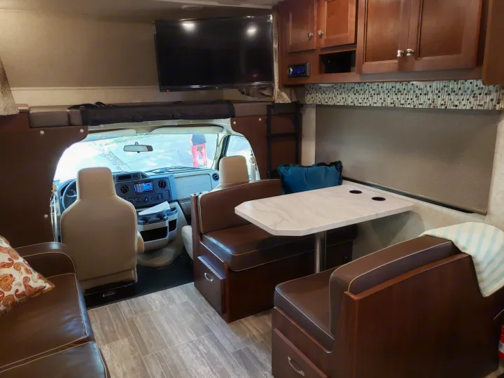 Spacious rv rental interior featuring a dinette, front driver's area, and over-cab bunk. Perfect for road trips!. Other Other 2019