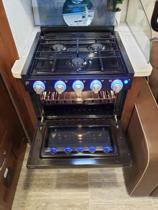 Modern black gas stove and oven in an RV rental kitchen. The control knobs glow blue, and the oven door is open.. Other Other 2019