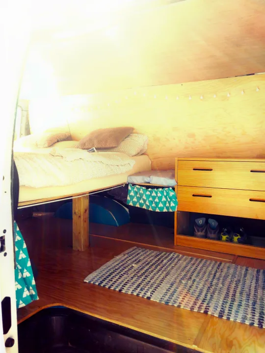 Experience the comfort of an rv rental: inviting bed, wooden storage, and a warm rug in this cozy camper interior.. Ford Econoline 2006