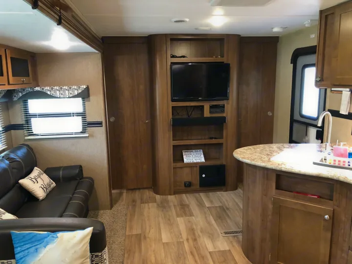 Explore the inviting living and kitchen interior of this RV rental, complete with an entertainment center for your comfort.. Dutchmen Aspen Trail 2018