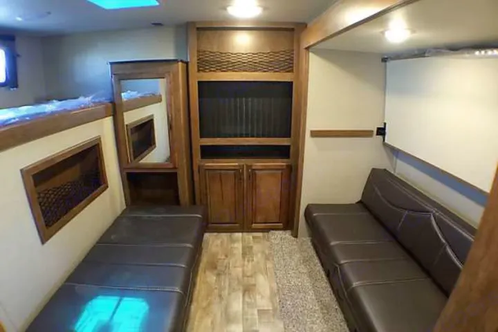 Spacious RV rental interior with bunk beds, two brown sofas, and a central entertainment cabinet. Perfect for your next adventure.. Grand Design Reflection 2016