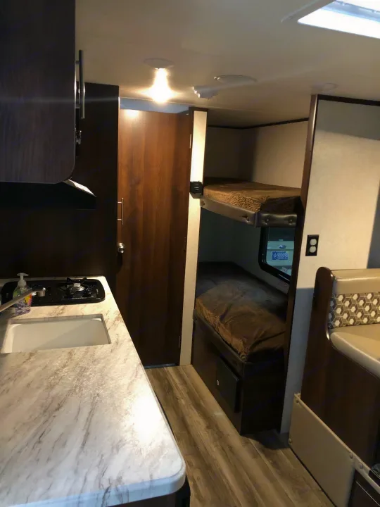 Cozy RV rental interior with kitchen, sink, stove, bunk beds, and dinette—ideal for family travel adventures.. Jayco Other 2020