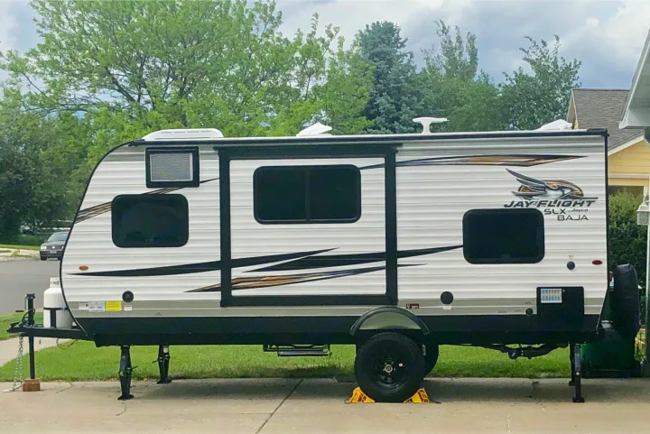 This travel trailer, a great option for an rv rental, is a white Jayco model with black trim, tinted windows, and stabilizer jacks.. Jayco Other 2020