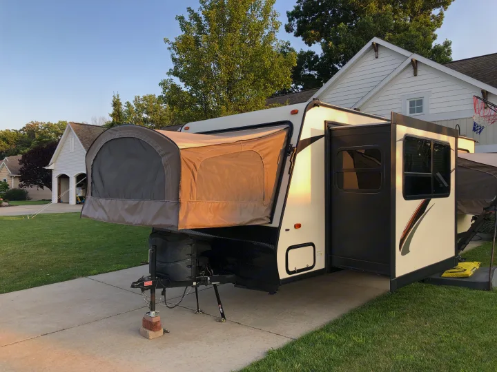 An RV rental, a hybrid camper with a fabric pop-out bed, parked on a driveway in a residential area.. Dutchmen Kodiak 2016