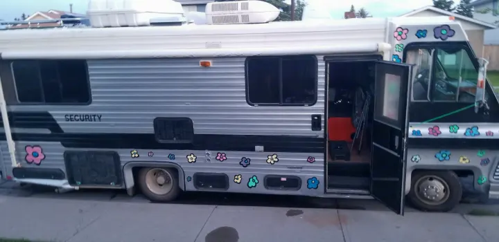 Check out this unique, silver and black RV, covered in colorful flower decals with "SECURITY" text. An ideal RV rental.. Chevrolet Other 1980