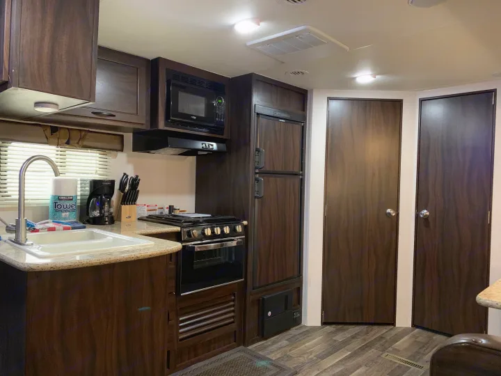 Modern RV rental kitchen interior: sink, stove, microwave, fridge, ample storage. Ready for your next road trip adventure!. Pacific Coachworks Tango 2020