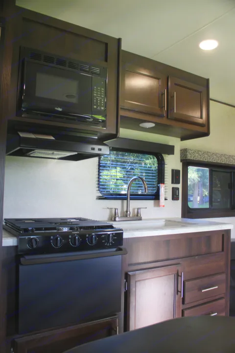 Enjoy home comforts in this RV rental kitchen, complete with a microwave, Dometic stove, sink, and dark wood cabinets for all your travel needs.. Jayco Jay Flight SLX 2019