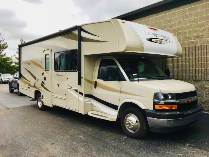 Side view of a cream-colored Coachmen Leprechaun Class C RV rental parked on asphalt, ready for adventure.. Coachmen Leprechaun 2018