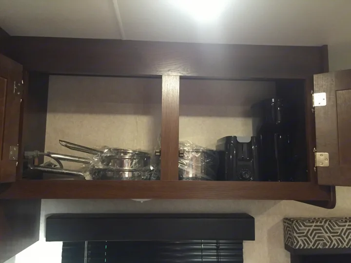 Overhead cabinet in an RV rental, stocked with new, plastic-wrapped pots and pans, a toaster, and a coffee maker.. Jayco Jay Flight SLX 2019