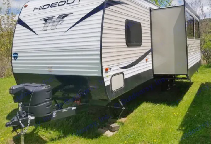 This Hideout travel trailer, a great rv rental option, is parked on grass with its slide-out extended, ready for adventures.. Keystone Hideout 2017