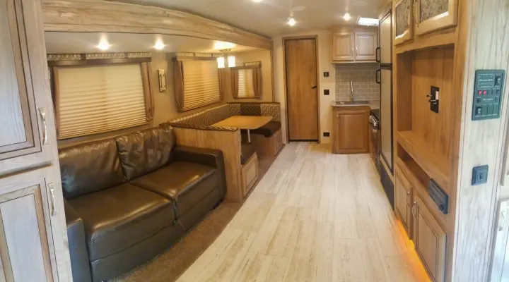 Well-appointed rv rental interior featuring a brown sofa, dining booth, and compact kitchen with light wood finishes.. Palomino Solaire Ultra Lite 268BHSK 2020