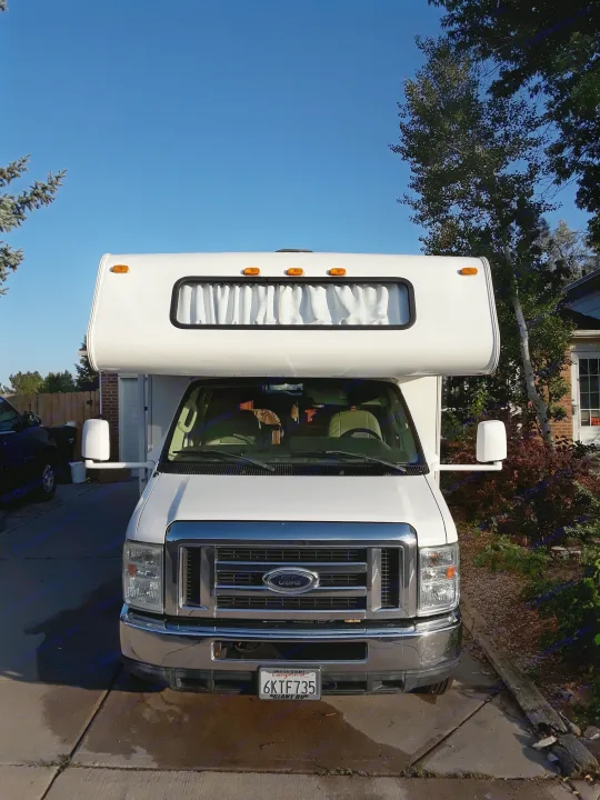 Bright white Ford **RV rental**, ready for adventure under a clear blue sky. Ideal for road trips and camping.. Coachmen Freelander 2011